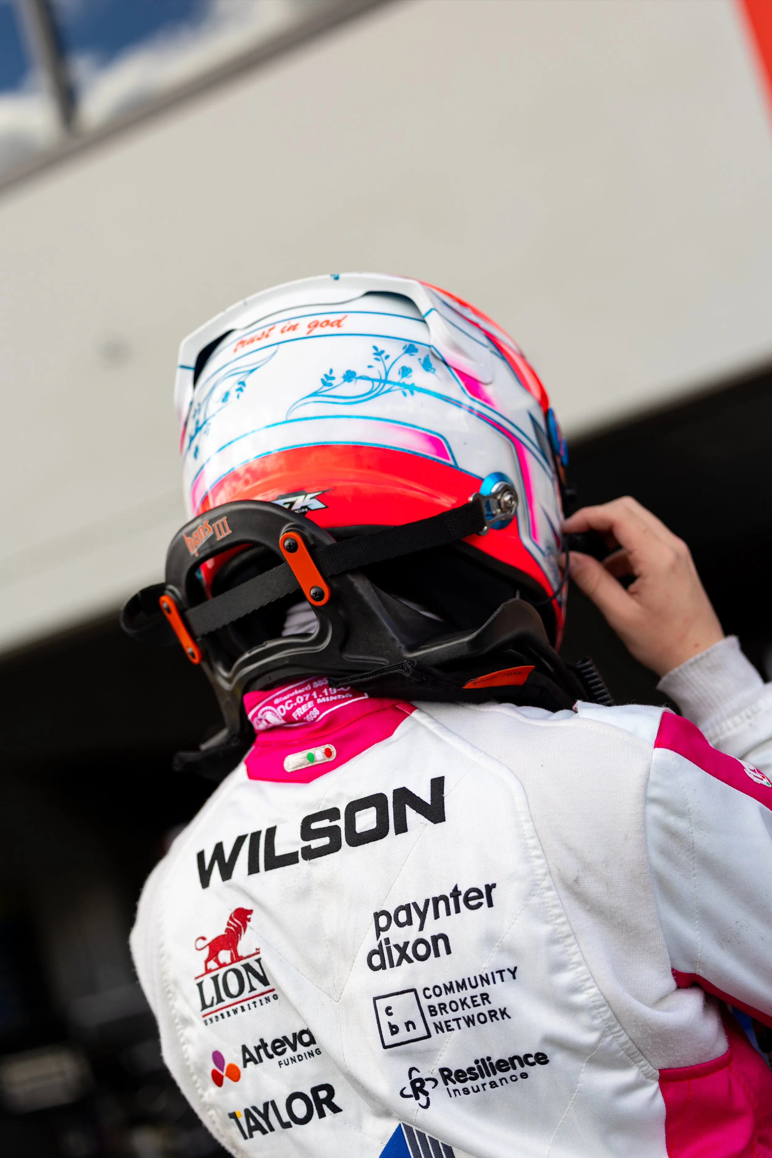 Koby adjusting his helmet, seen from behind with WILSON across his shoulders