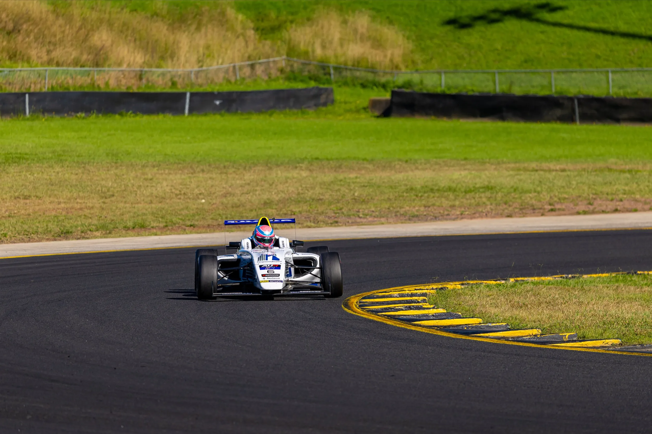 Koby's car clipping the yellow and black kerb at the apex of a corner